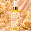 A bottle of The Candi Shop Buttercreme Frosting Luxury Gourmoud Body Oils, styled on a champagne-colored satin background with a cupcake, pearls, and flowers.