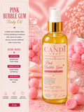 A bottle of The Candi Shop Pink Bubble Gum Luxury Body Oil centered on a pink background with candy-themed props and a scent-notes panel on the left.